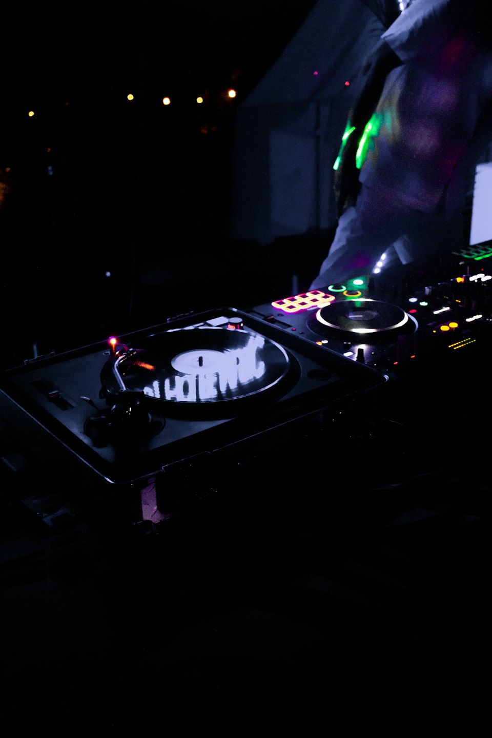 DJ che mixa musica su giradischi con luci colorate.