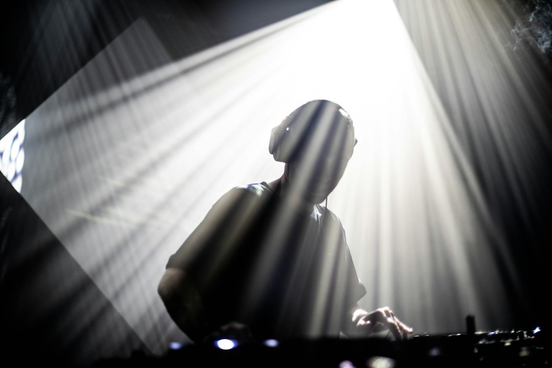 DJ in silhouette with headphones on a stage.