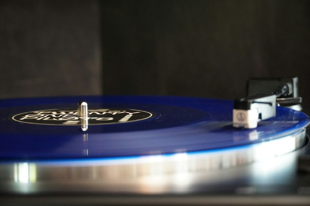 A stylus rests on a blue vinyl record spinning on a turntable.